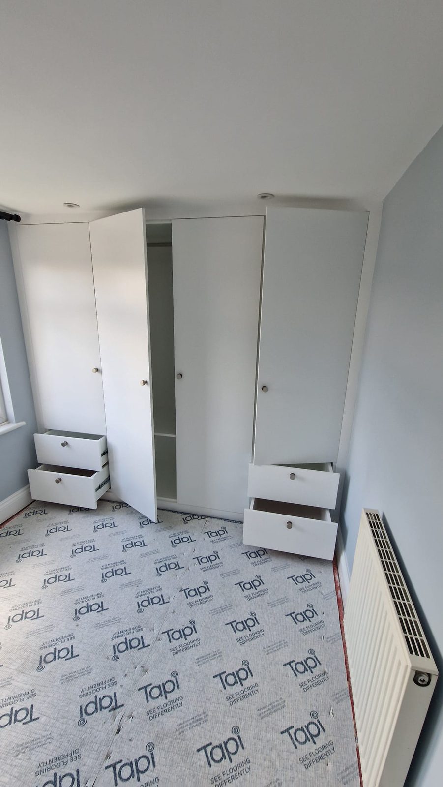 Bespoke white fitted wardrobes around a chimney breast by AG Signature Renovation