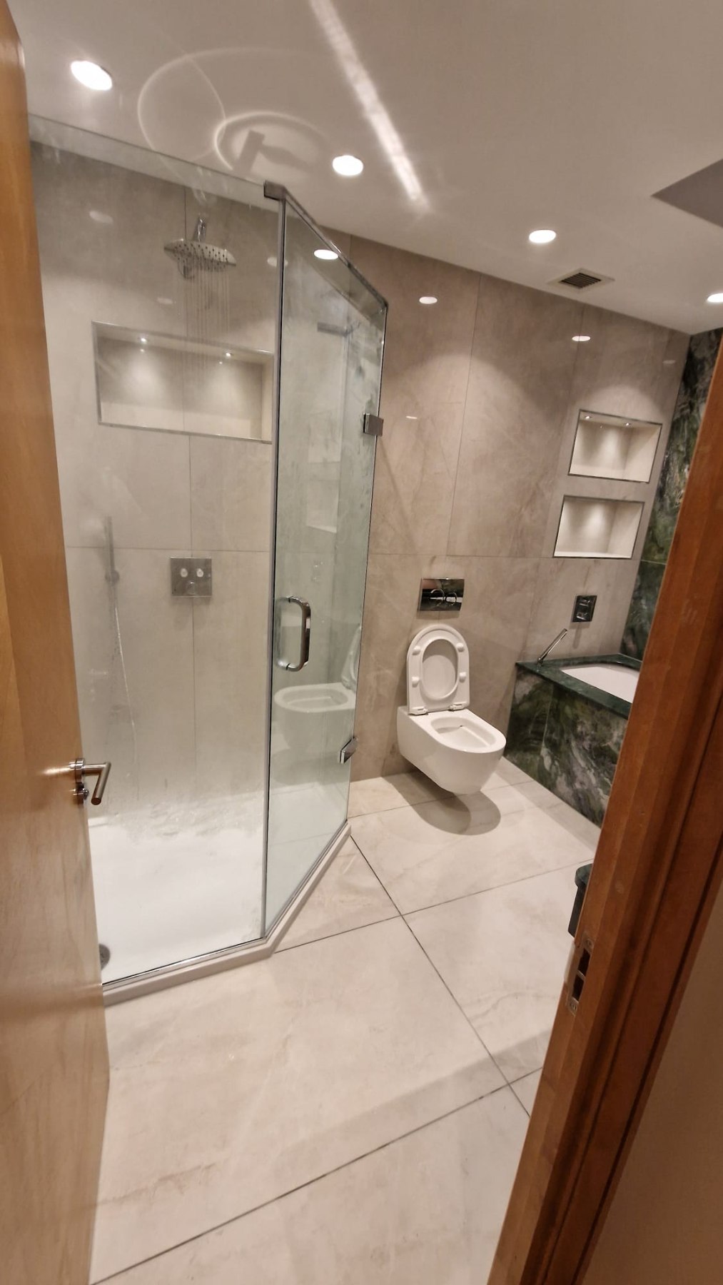Bathroom with green marble bath surround by AG Signature Renovation